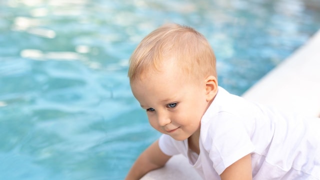 Niño pequeño metiendo la mano en una piscina con riesgo de ahogamiento
