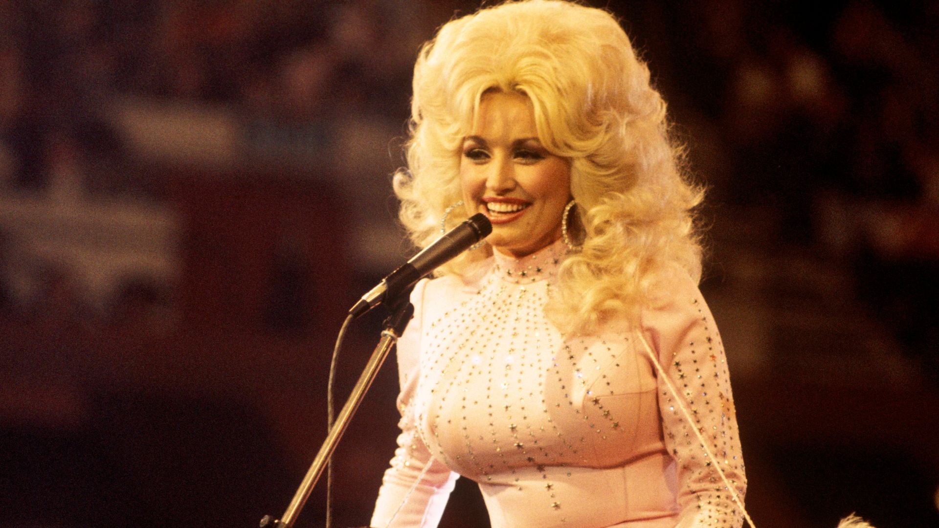 American singer, songwriter and actress Dolly Parton, performs with a guitar, 1976