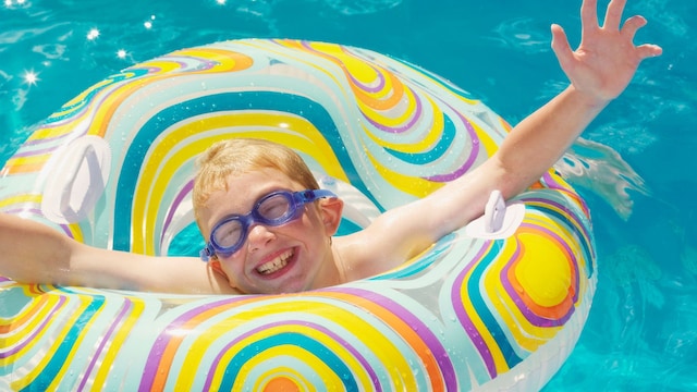 Niño sonriendo dentro de un flotador en la piscina