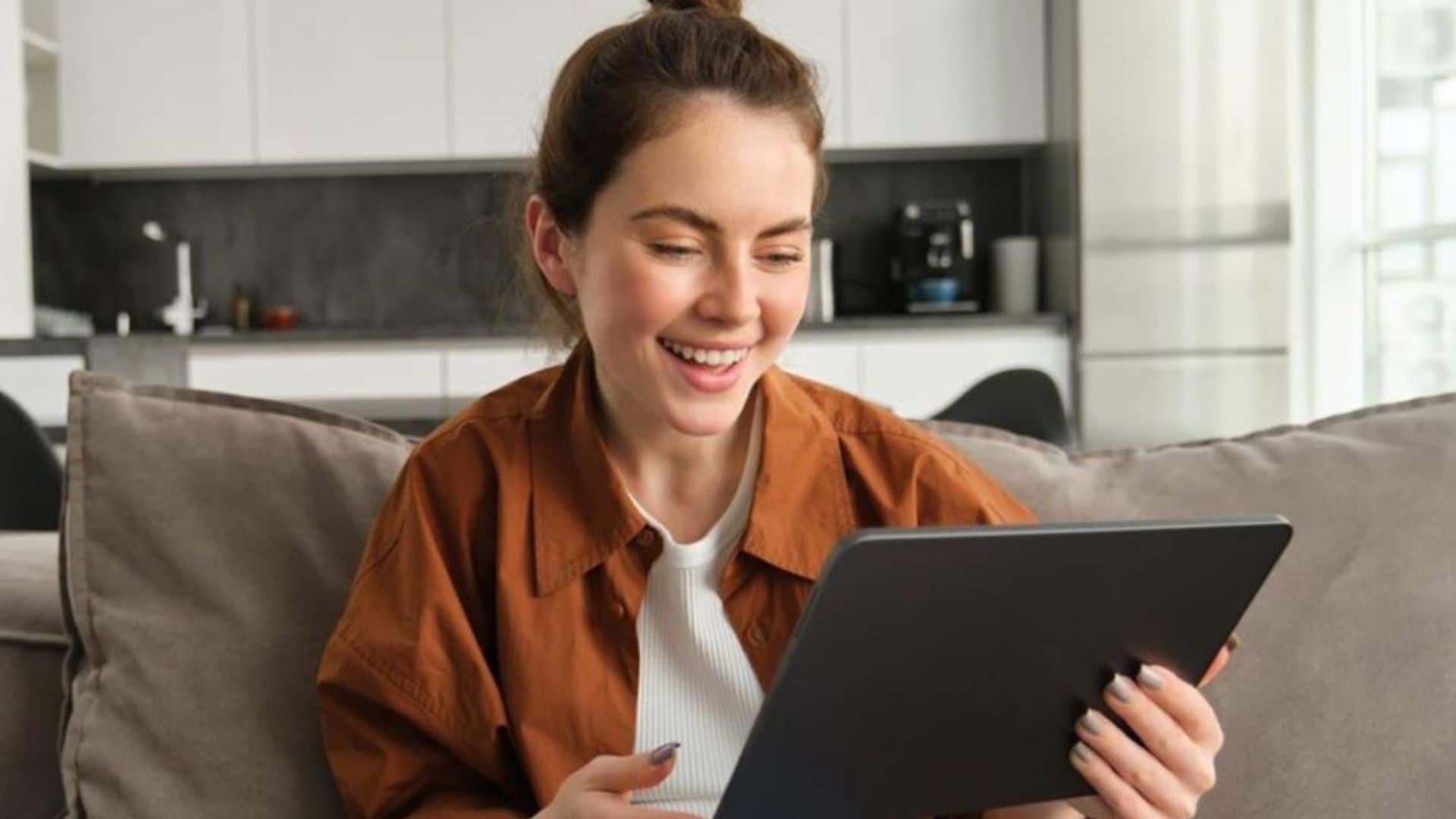 Mujer en su salón mirando sonriente su tablet