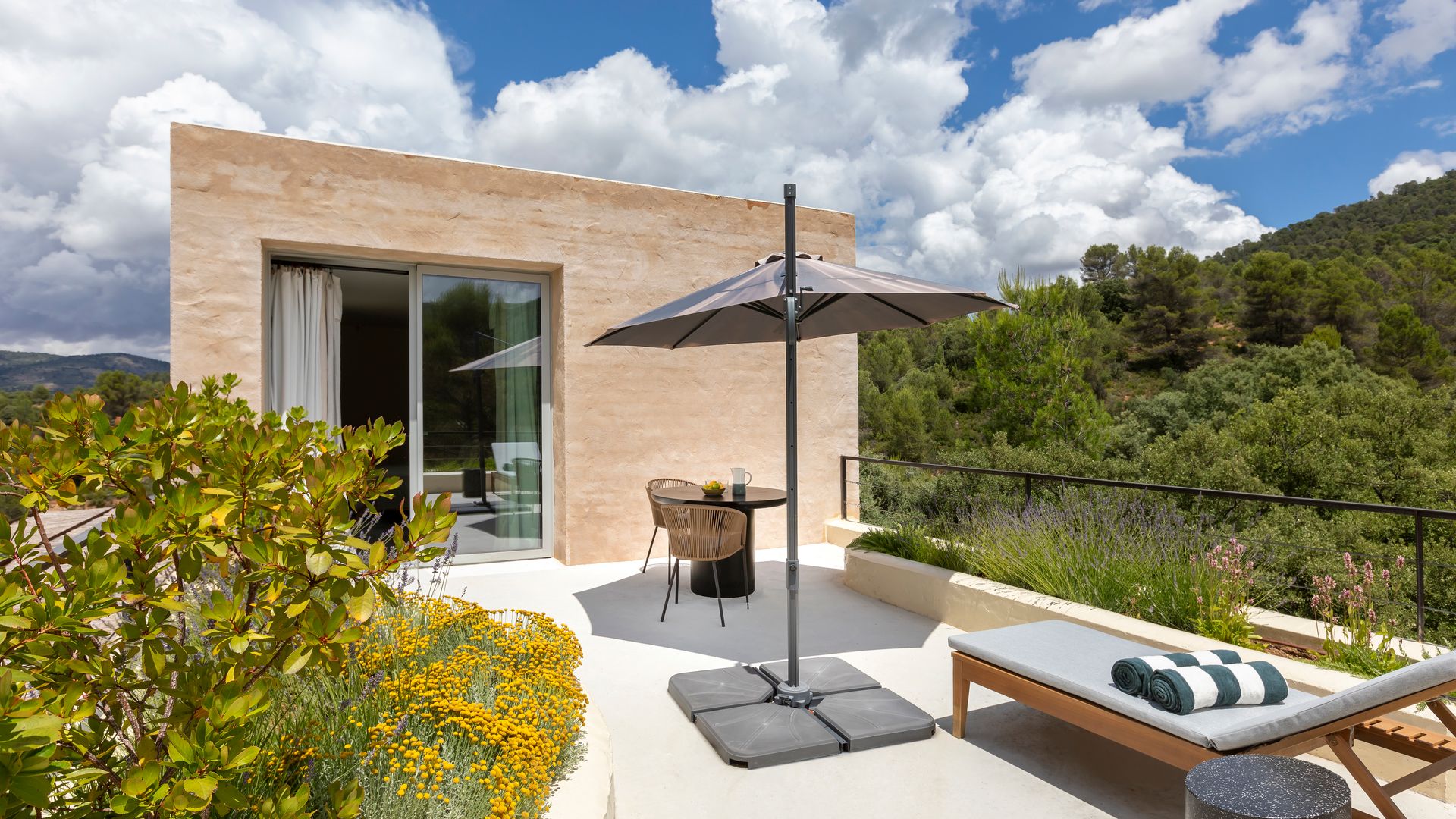 Exterior casa de campo con terraza, sombrilla, hamaca y mesa con silla