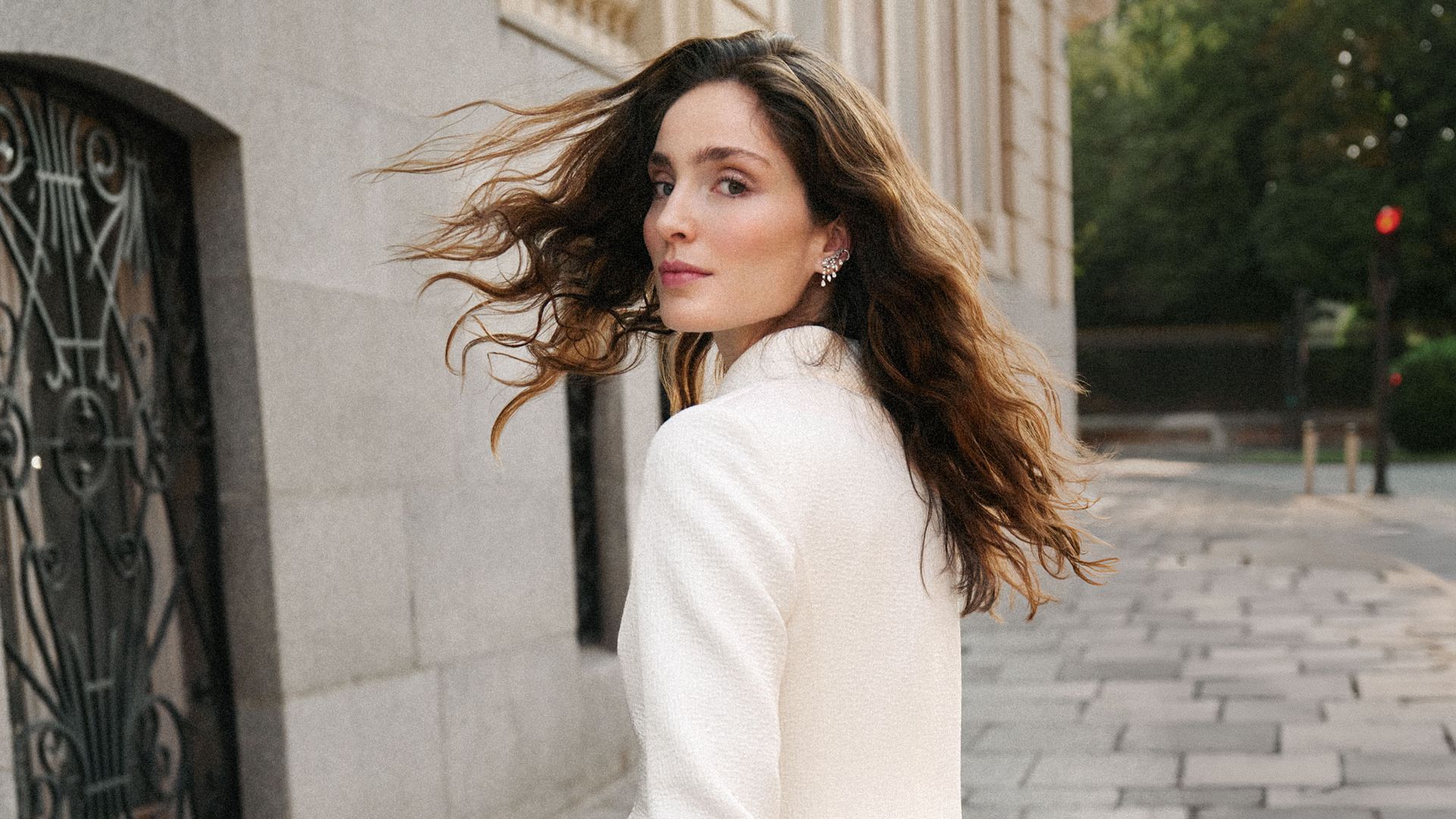 Lleva americana con detalle de lazo, falda 'midi' asimétrica de plumas en blanco y negro y sandalias blancas, todo de Dior, y pendientes 'earcuff' de oro blanco con diamantes, de Rabat