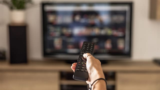 Una chica cambiando la tele con un mando a distancia