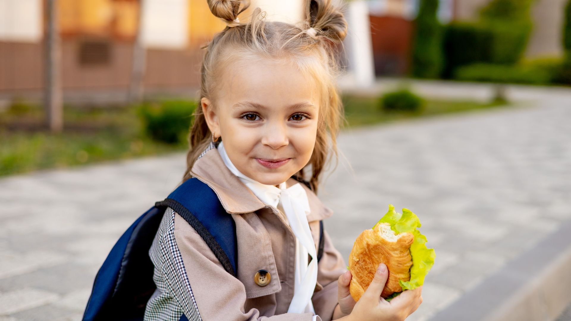 niña con un bocadillo y la mochila del cole