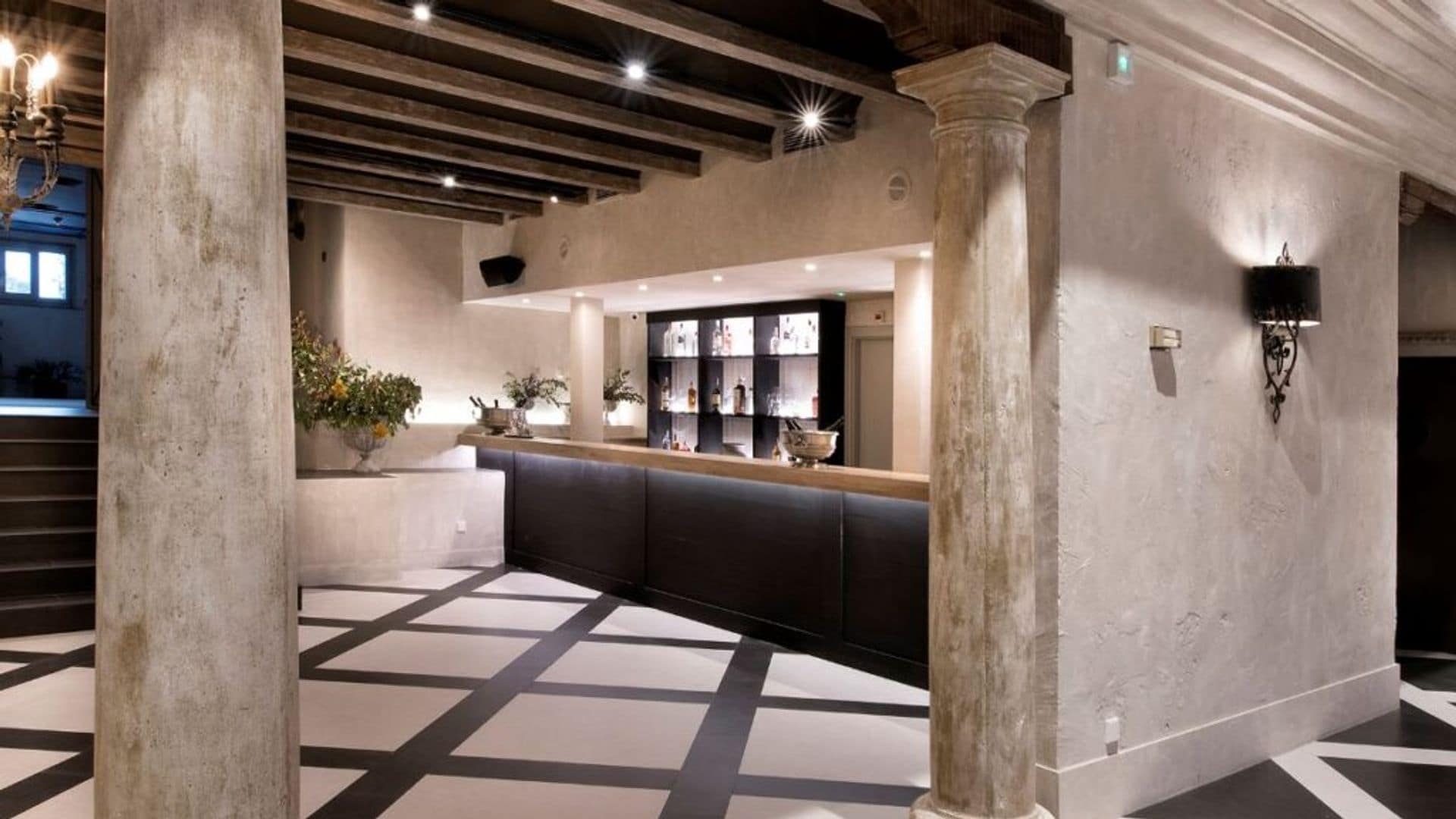 Entrada con columnas, suelo con motivos geométricos en blanco y negro, aplique de pared, molduras en el techo 