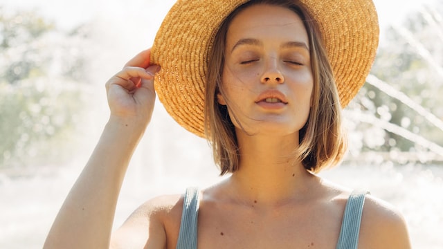Mujer con la cara descansada y con un sombrero en verano