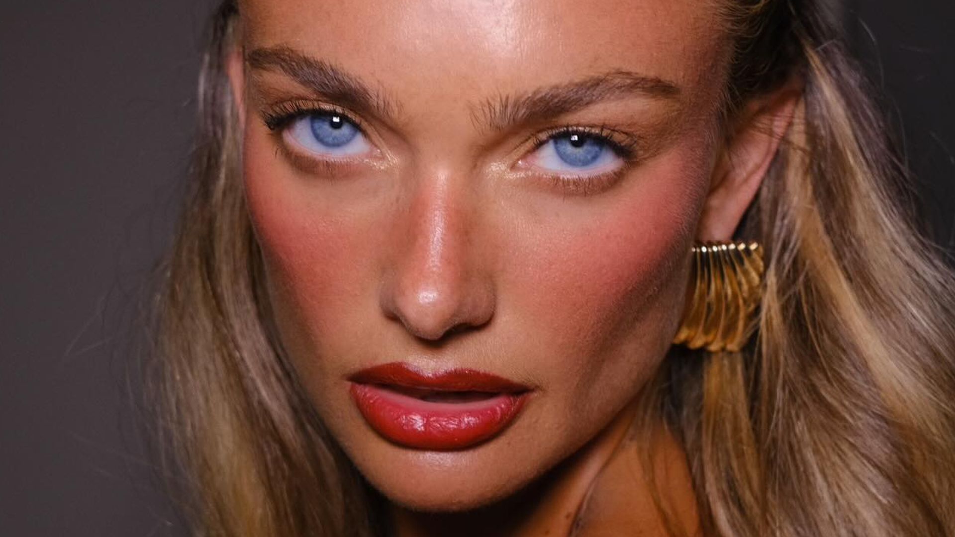 Lilia Rose en primer plano con maquillaje natural centrado en las mejillas y labios rojos