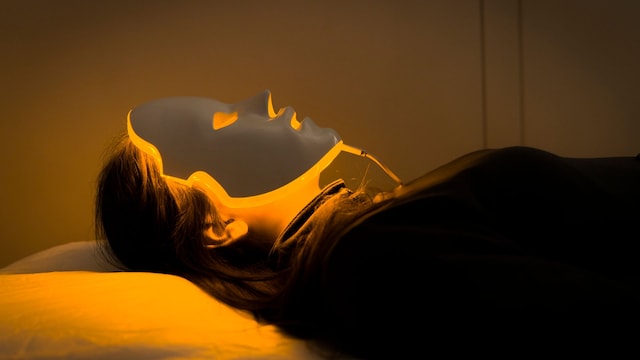 Mujer tumbada con máscara Led facial en el rostro