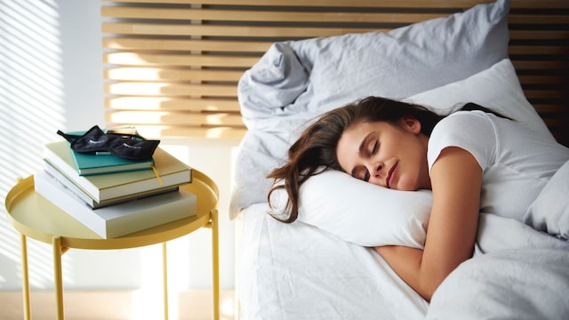 Mujer durmiendo y descansando en una cama abrazando su almohada