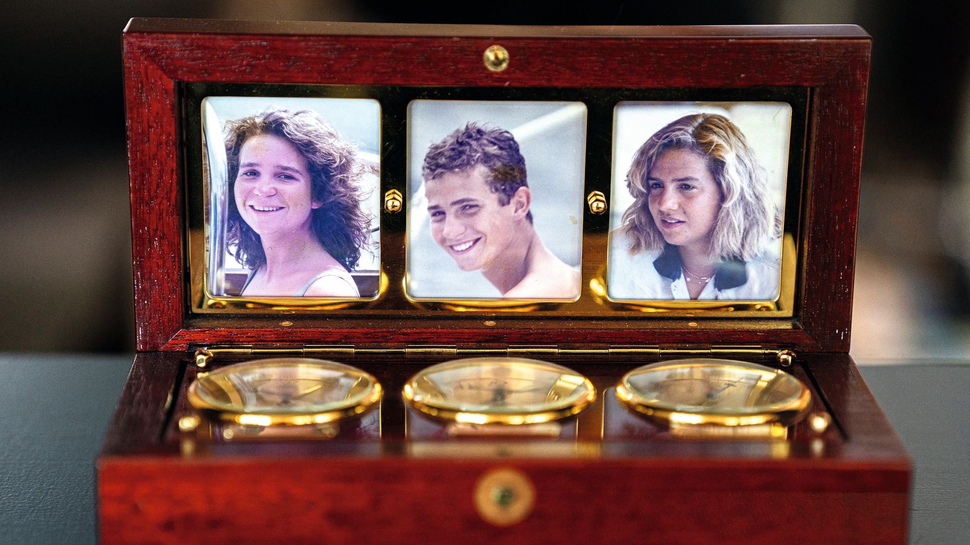 Fotografías del rey Felipe VI y las infantas Elena y Cristina dentro de una caja con tres brújulas marinas