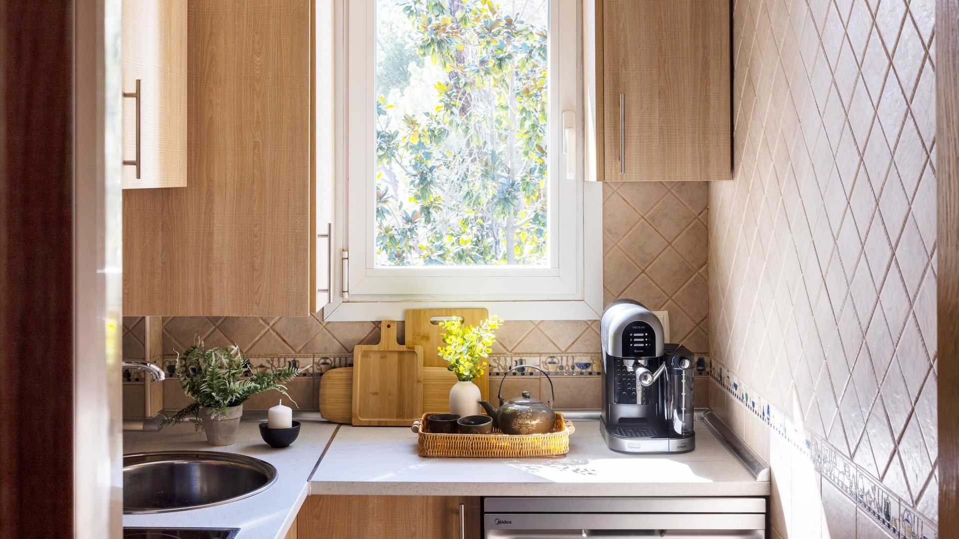 Cocina pequeña con azulejos, ventana y cafetera