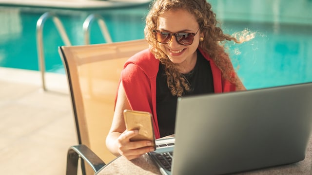 Comunicación, Internet, Piscina, Teléfono móvil, Webcam. Mujer rubia comprando en línea en un hotel resort.
