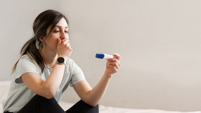Mujer mira, con cara de preocupación, el resultado de un test de embarazo