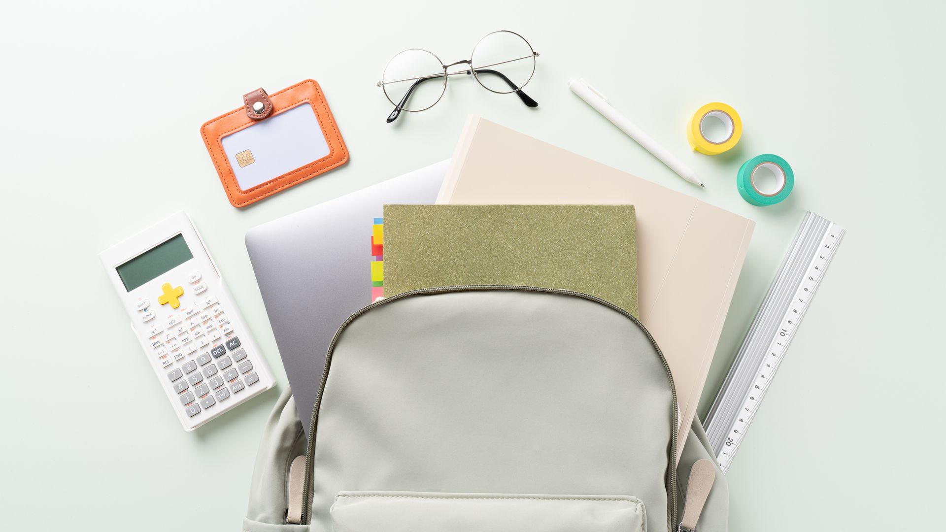 Mochila de colegio con el material escolar saliendo de ella, está tumbada sobre una mesa