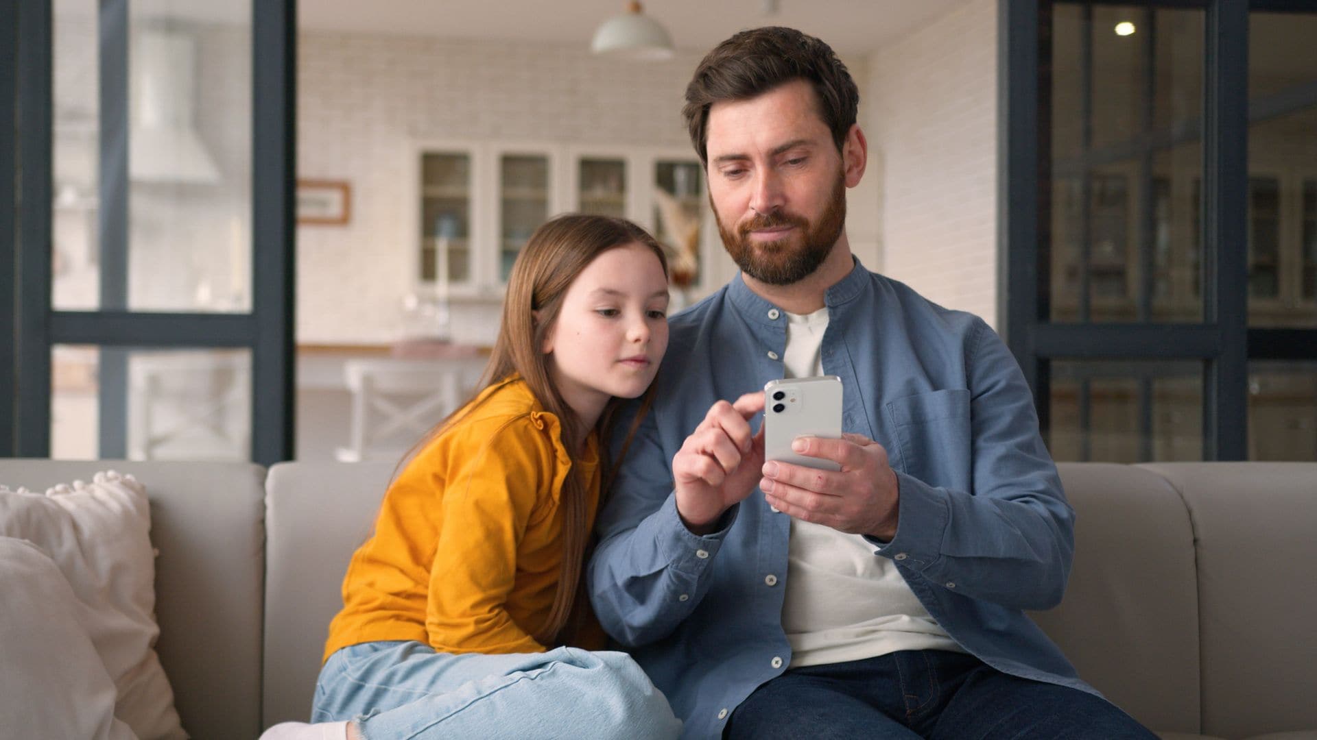 Padre con su hija adolescente viendo el móvil