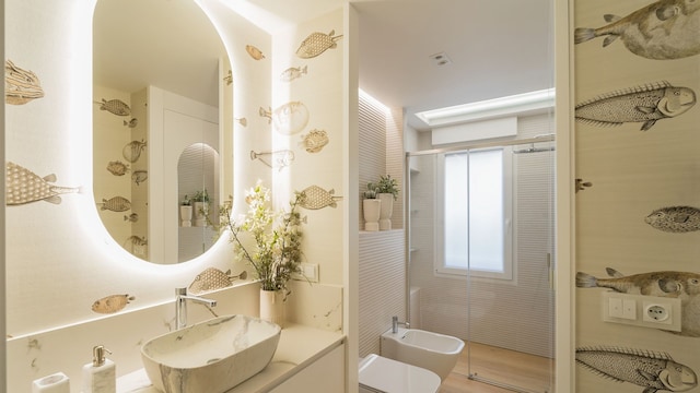 Baño con papel pintado de peces, espejo ovalado retroiluminado, lavabo sobre encimera, sanitario y bidé suspendidos