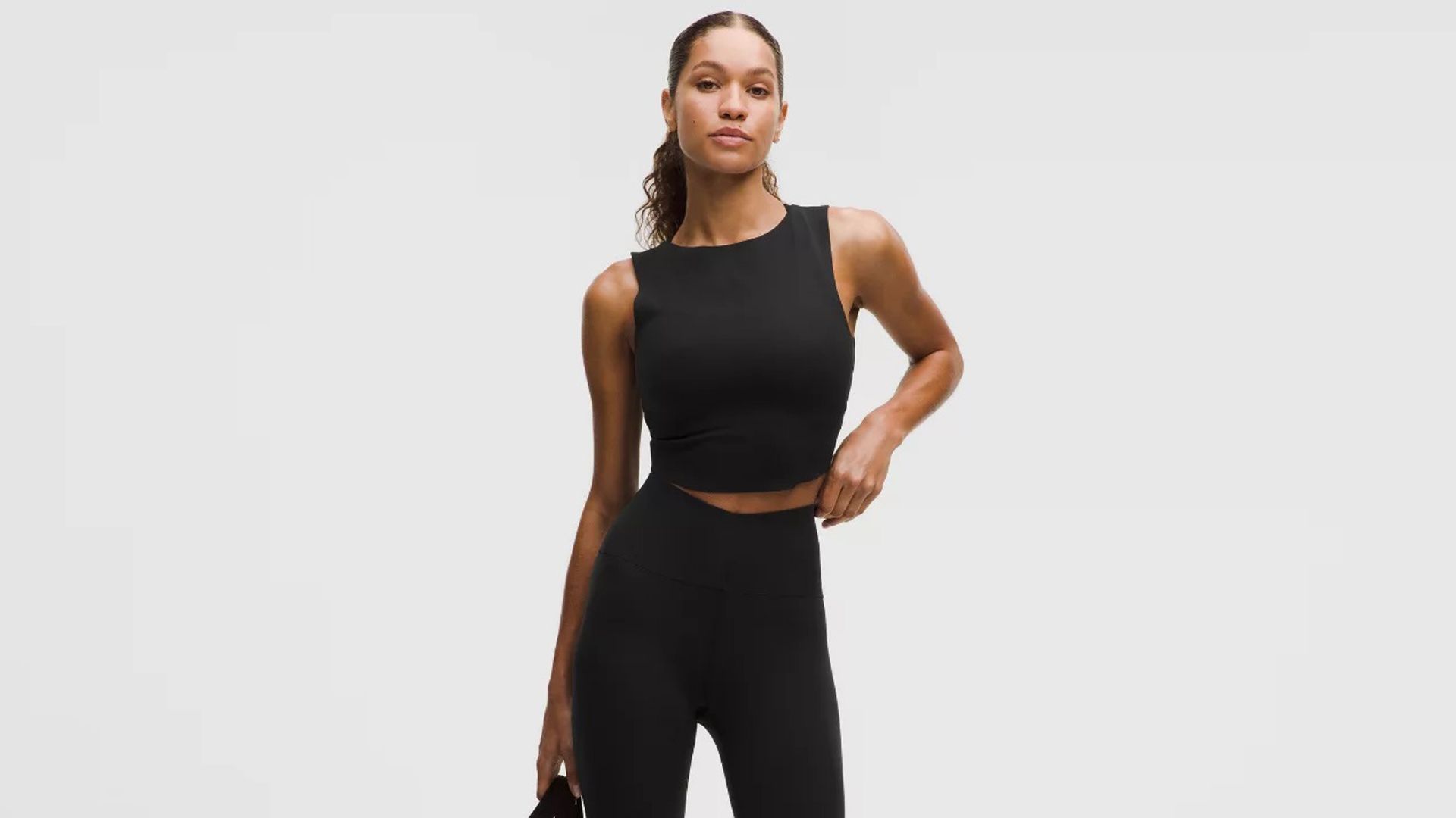 Mujer con leggings, bolso y top deportivo de Lululemon en color negro
