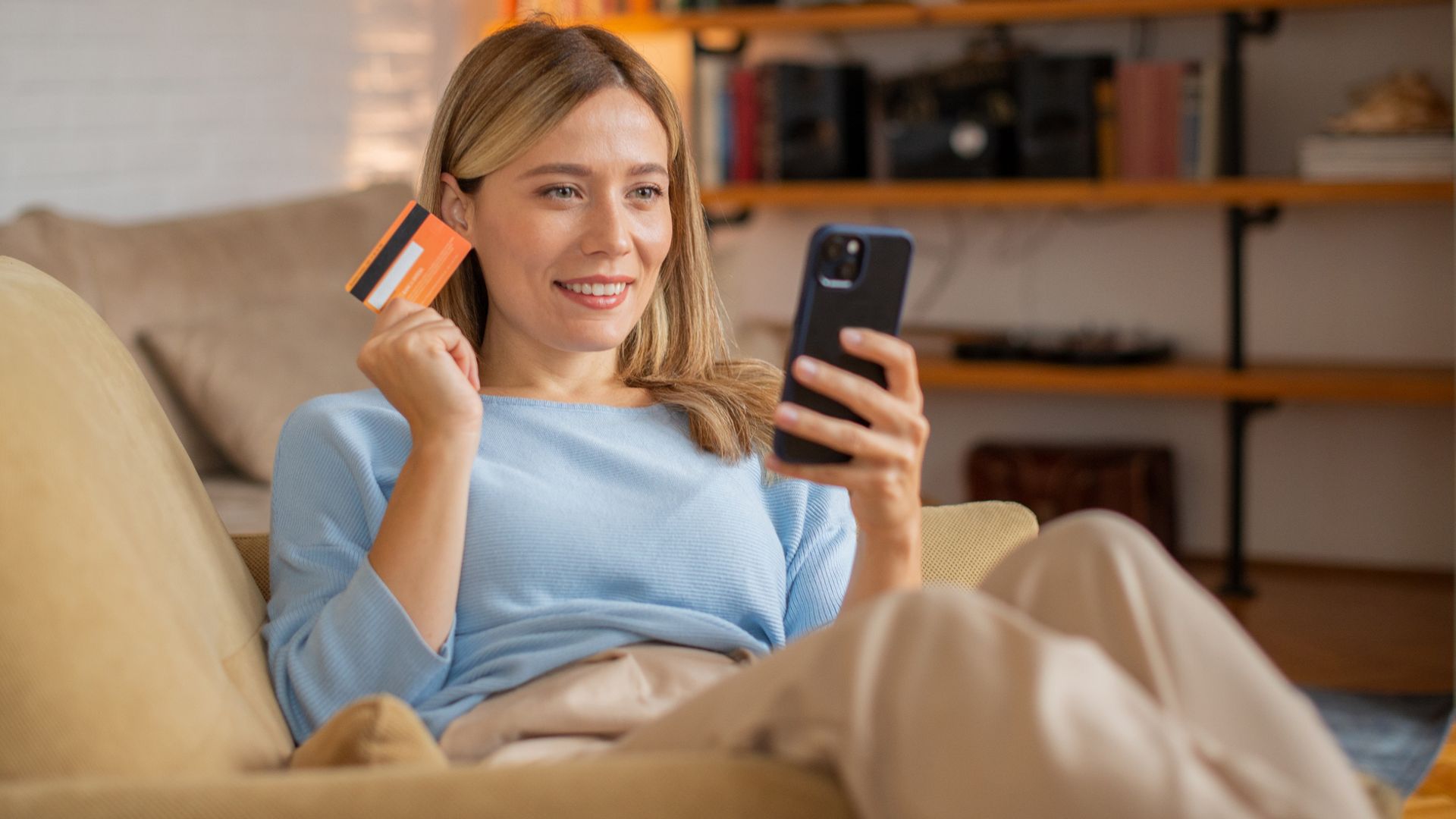 Mujer comprando por Internet en el salón de su casa, a través de su teléfono móvil.