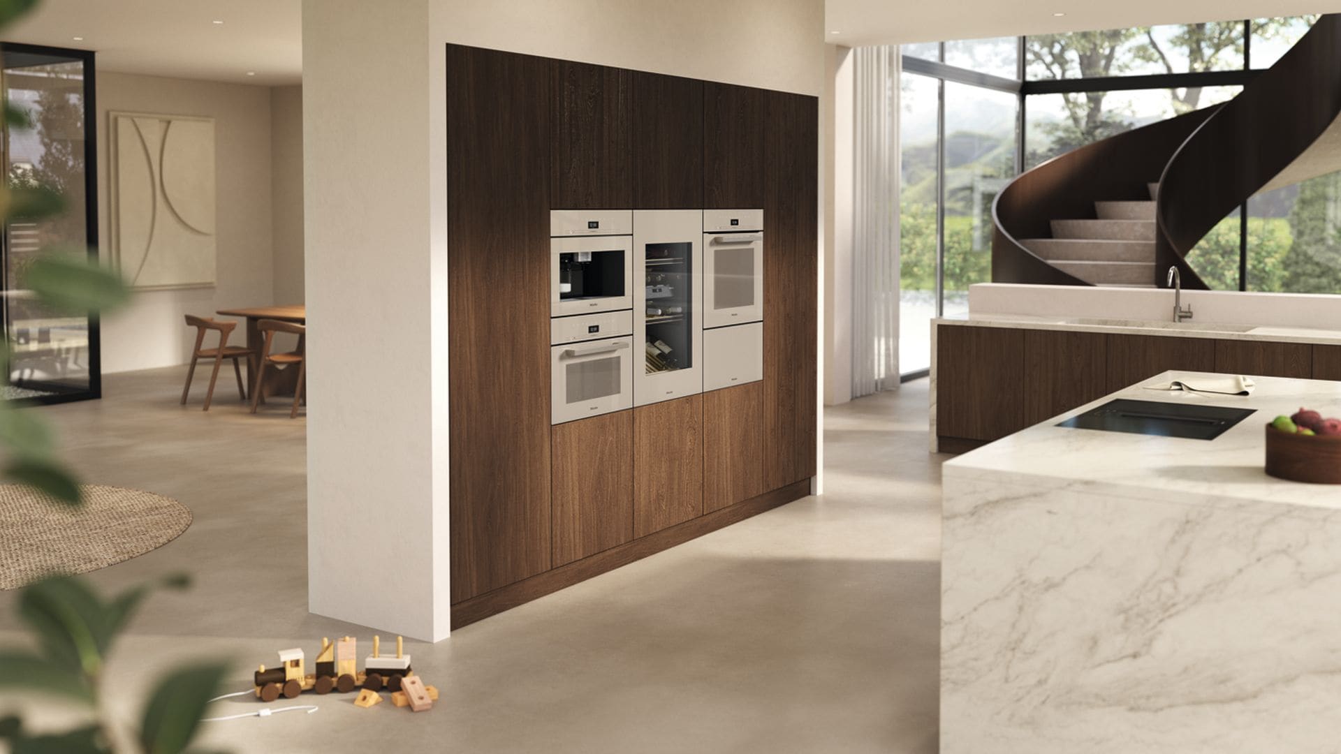Cocina con isla de mármol, frente de electrodomésticos en madera, lavavajillas integrado, escalera y grandes ventanales