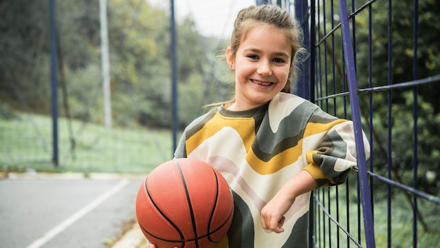 Niña sonriente con balón de baloncesto