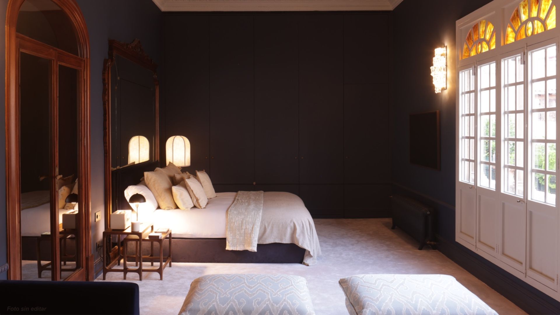 Dormitorio con paredes azules oscuras, techo decorado, vidrieras en las ventanas de salida al jardín, ropa de cama blanca, moqueta blanca