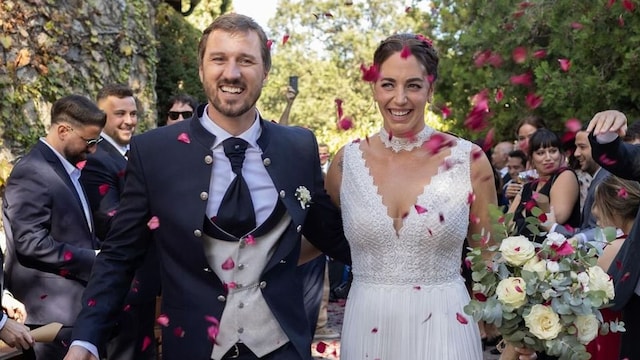 Plano entero de Maica García caminando con su novio en su boda mientras le tiran pétalos
