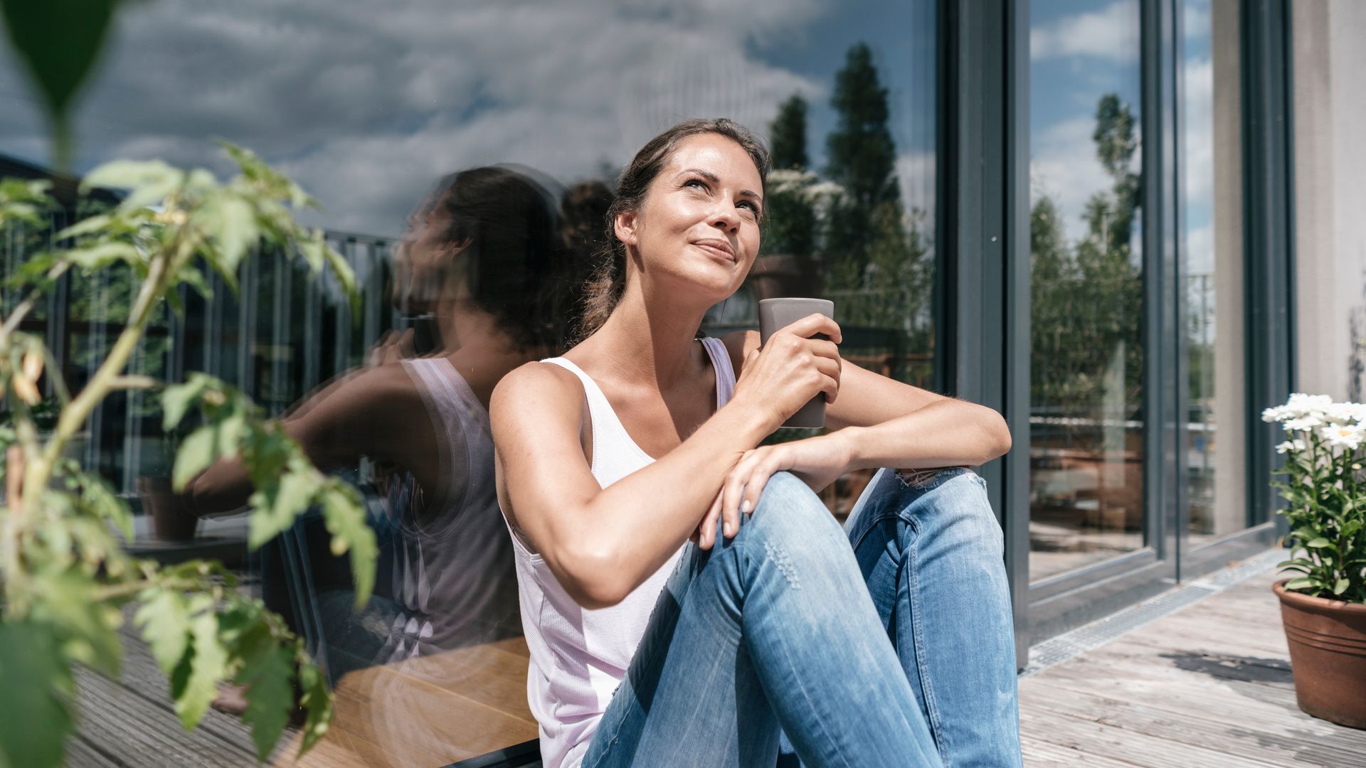 Mujer en una terraza tomando una infusión y mirando el sol