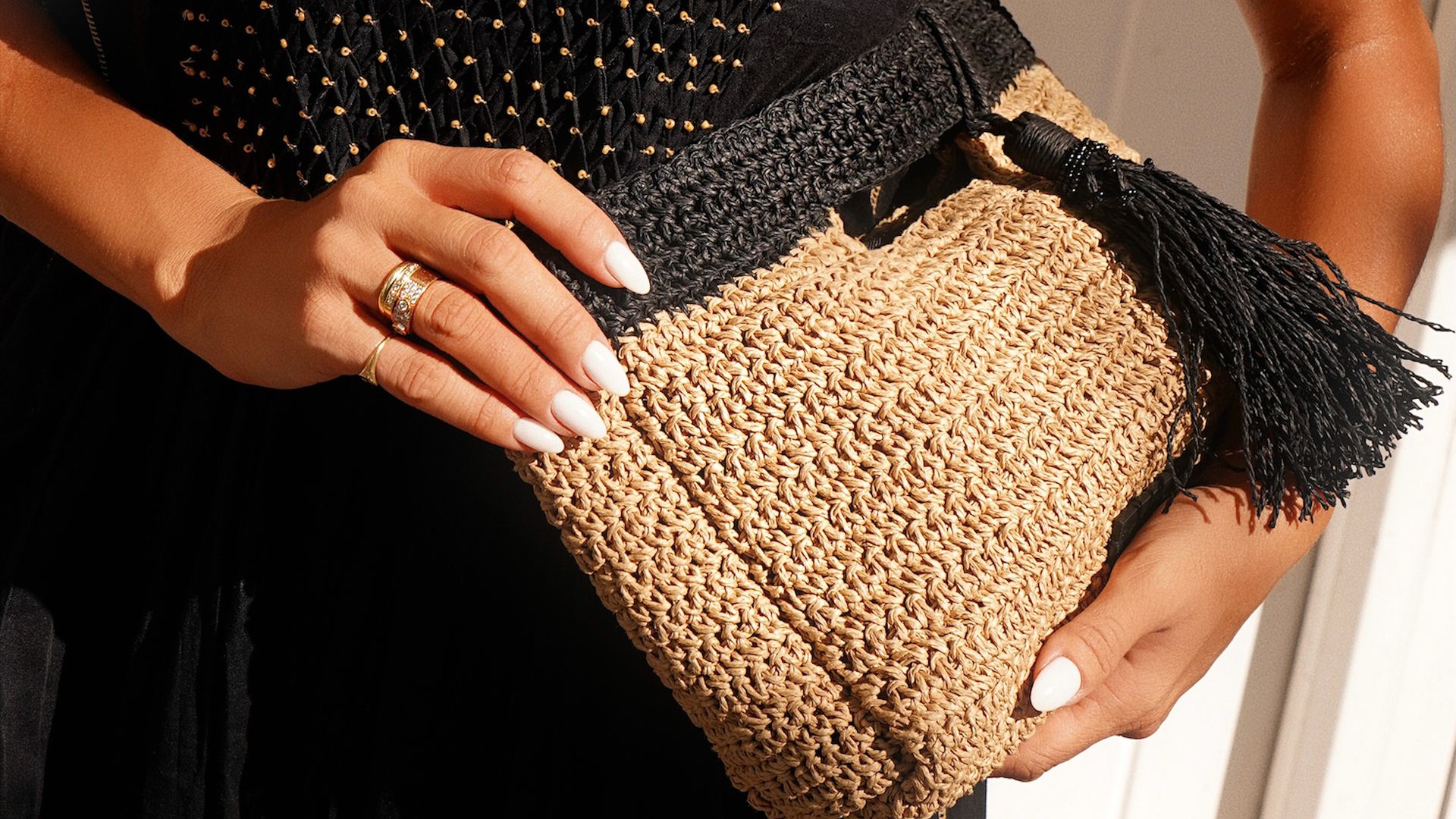 María Fernández-Rubíes con vestido negro halter, bolso de rafia y manicura blanca
