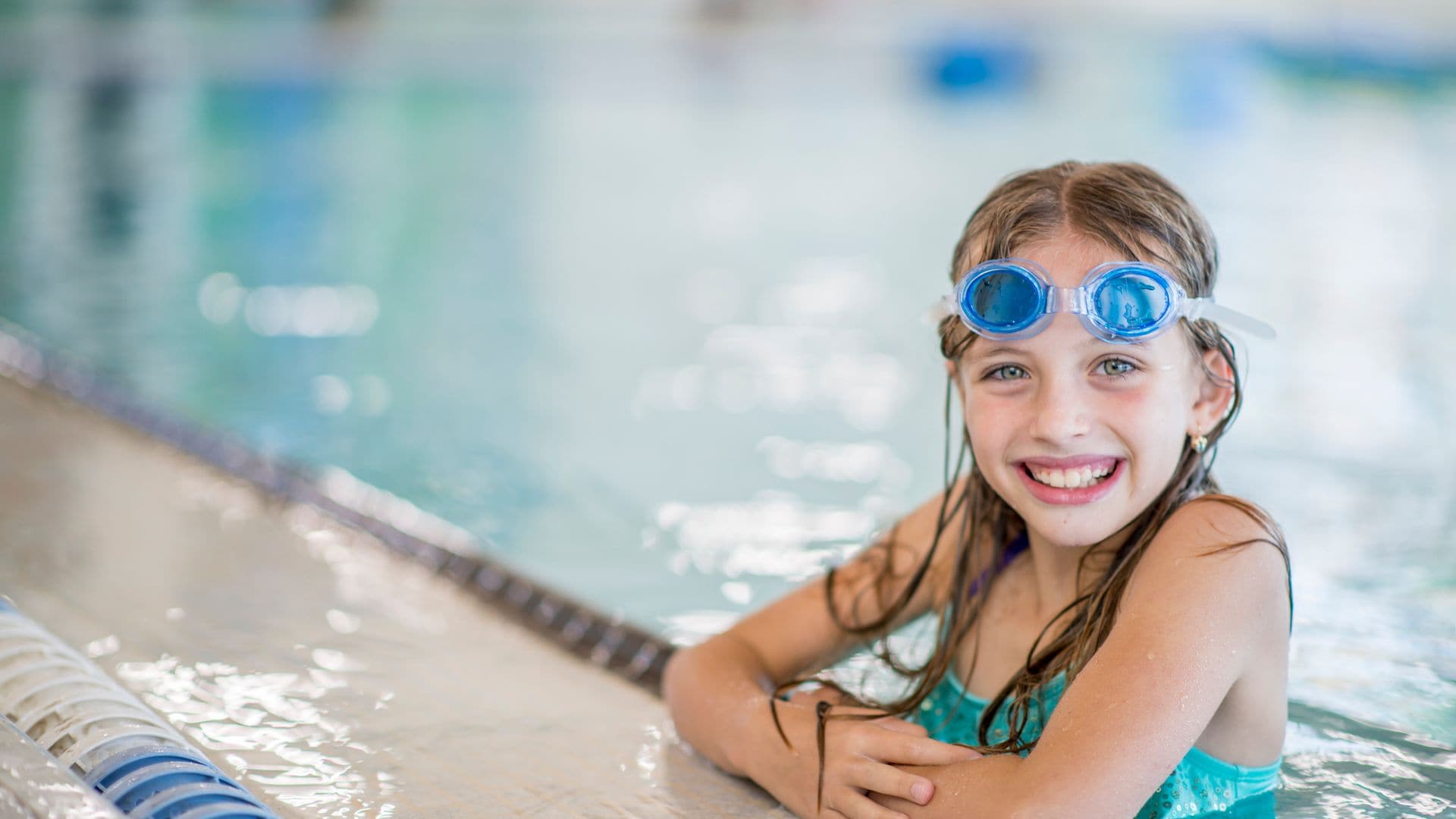 Niña en la piscina con gafas de agua