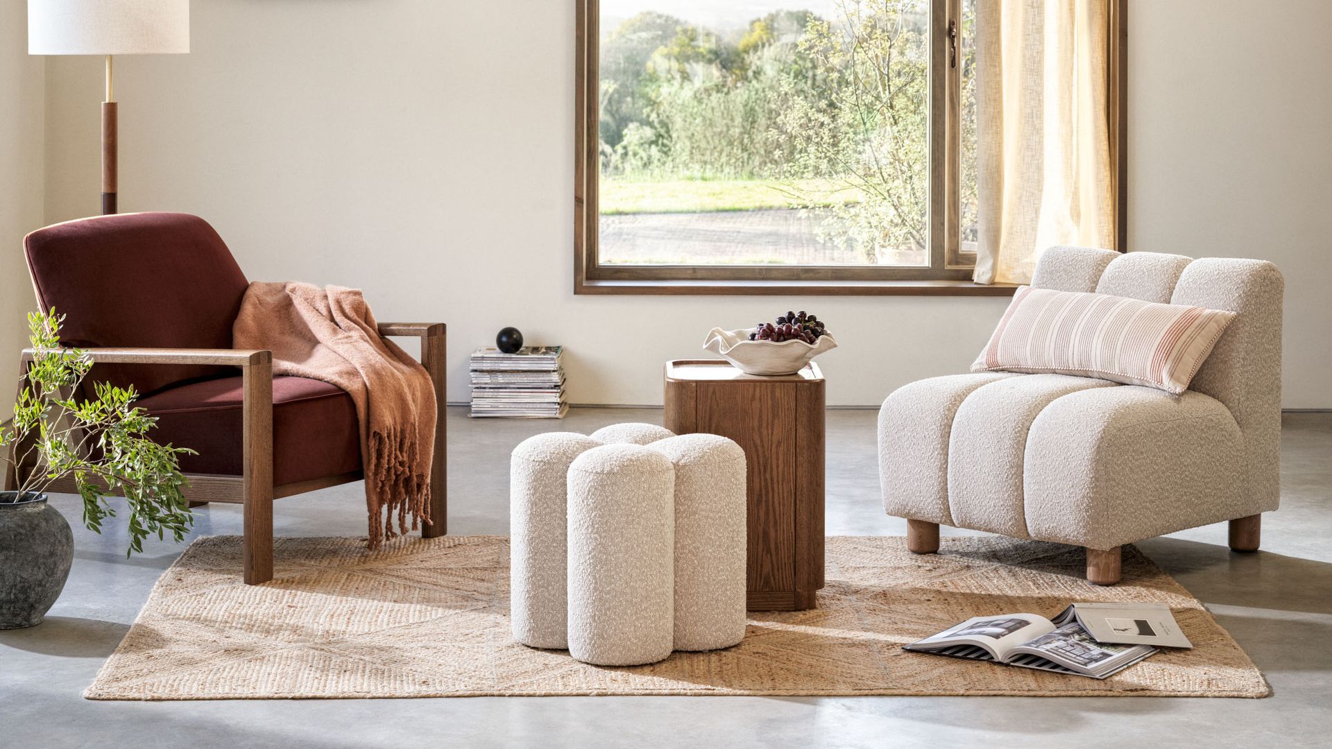 Salón sin sofá con butaca y sillón, alfombra, mesas auxiliares que sustituyen a la de centro, cortinas, lámpara de techo, gran ventanal, lámpara de pie