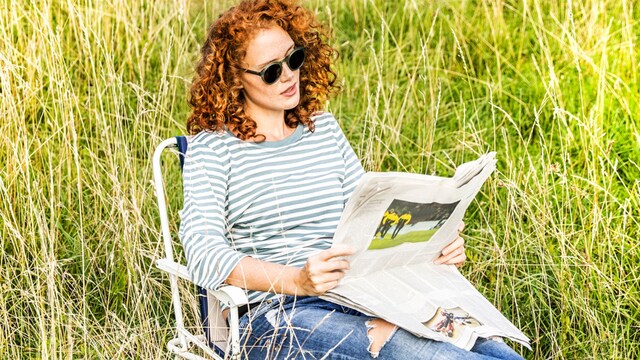 Mujer pelirroja leyendo el periódico
