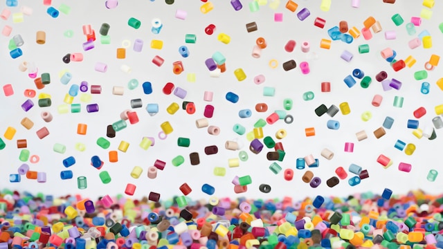 Lots of colored hama beads falling, cached in the air.
