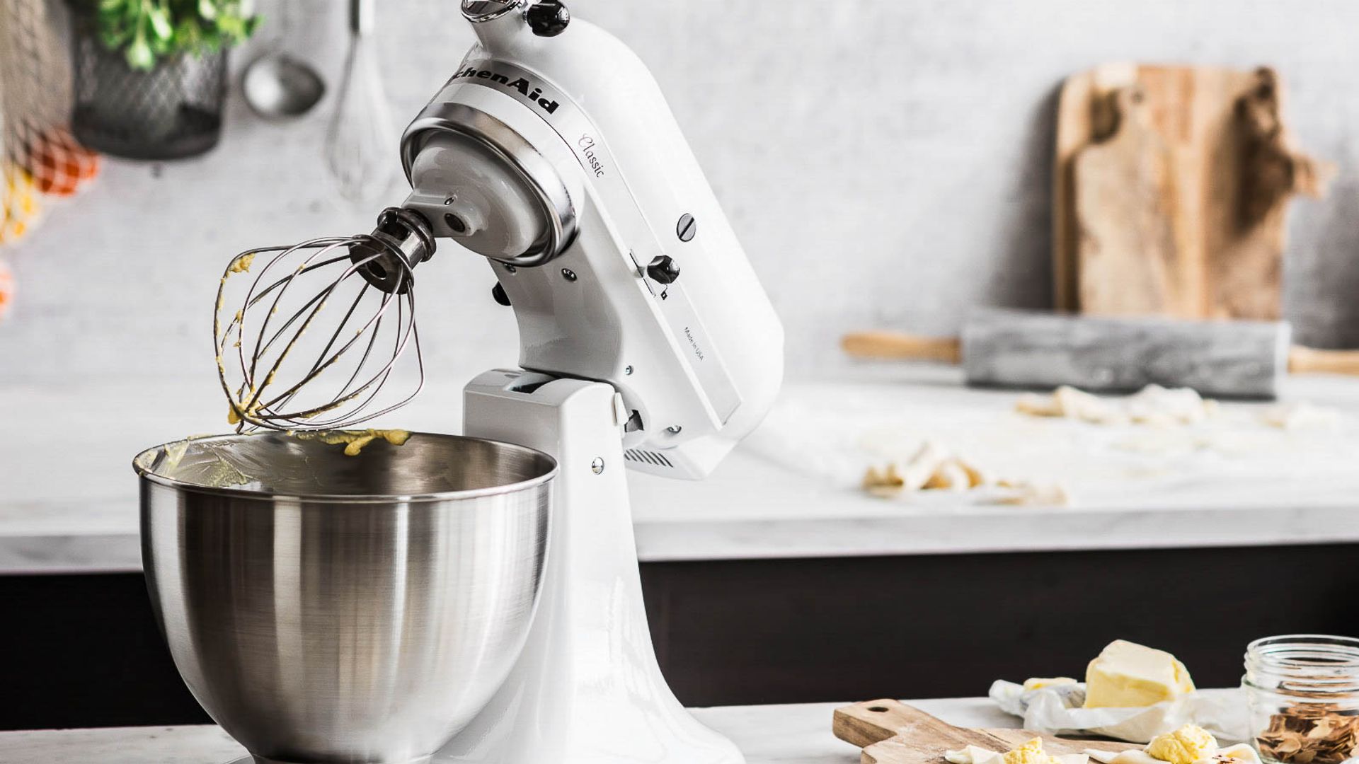 Una Kitchen Aid en blanco sobre una encimera de mármol haciendo pasta casera
