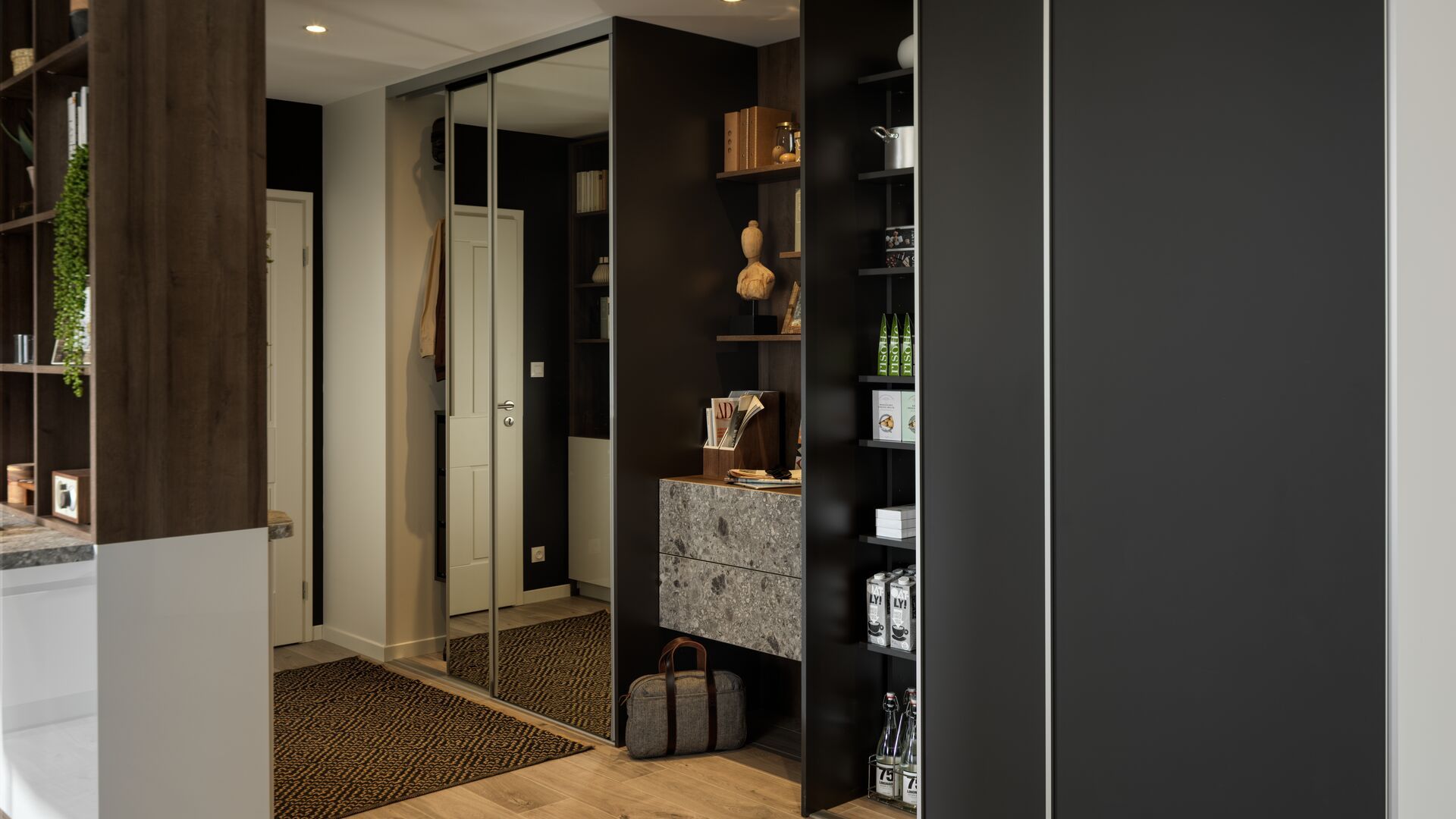 Recibidor abierto con mueble con armario con puertas de espejo, parte abierta con aparador, baldas con botellas y cajas 