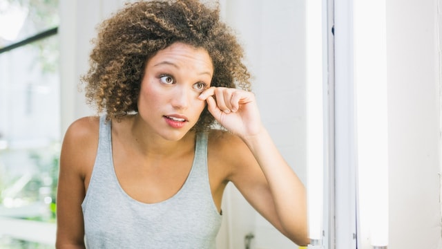 mujer mirándose el ojo frente al espejo