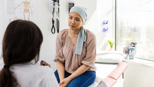 Una mujer con un pañuelo en la cabeza escucha a su doctora