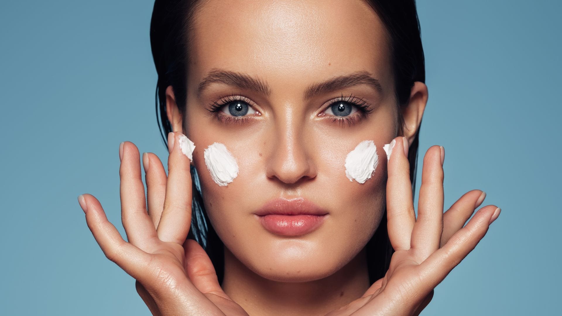 Mujer crema cara fondo azul