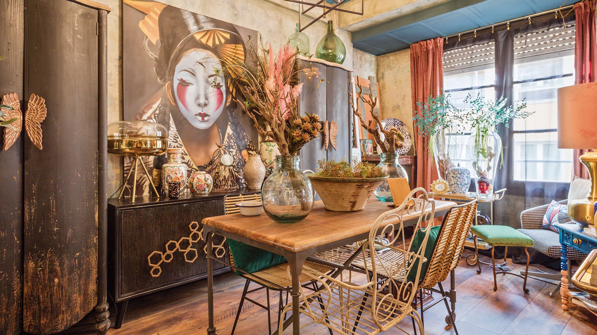 Comedor de estilo ecléctico, con muebles chinos, mesa de madera, sillas de fibras vegetales,. cuadro XL sobre aparador, jarrones, butaca, cortinas 