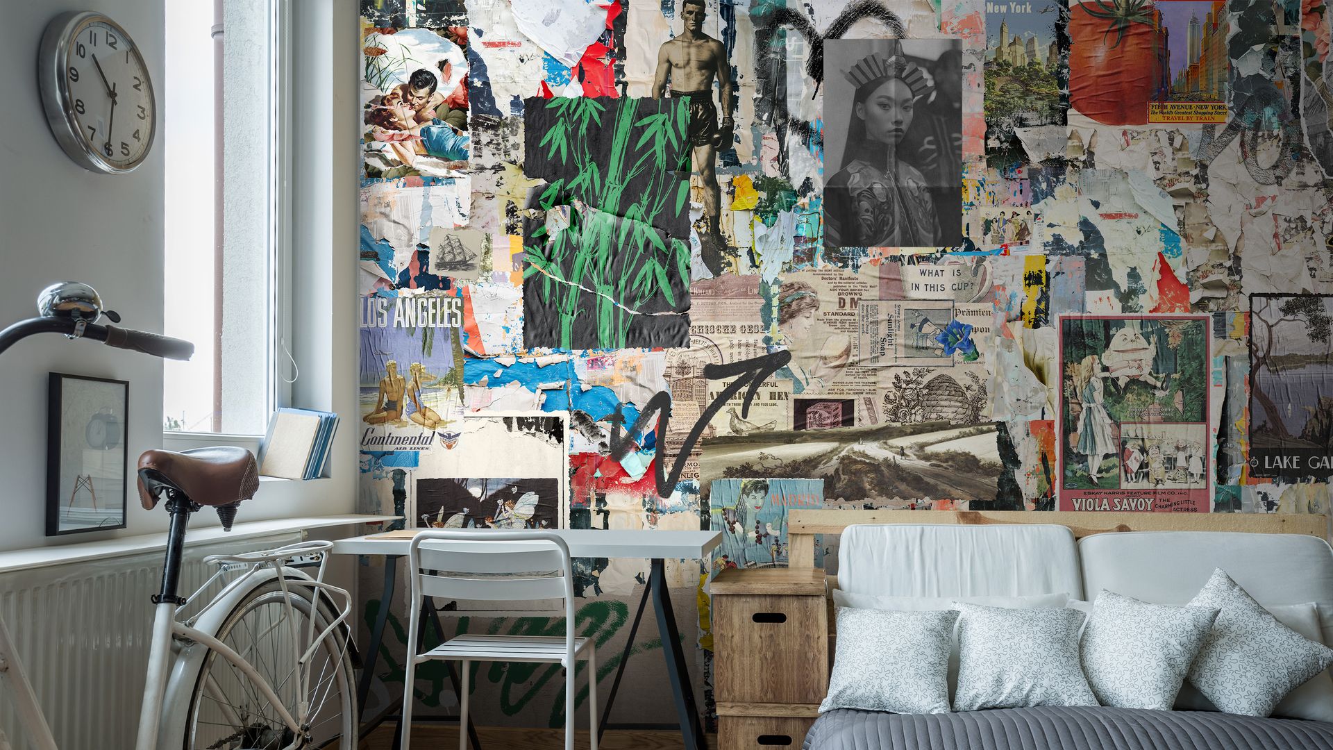 Dormitorio con papel pintado a modo collage en la pared del cabecero, bicicleta, mesa y silla de escritorio, reloj en la pared