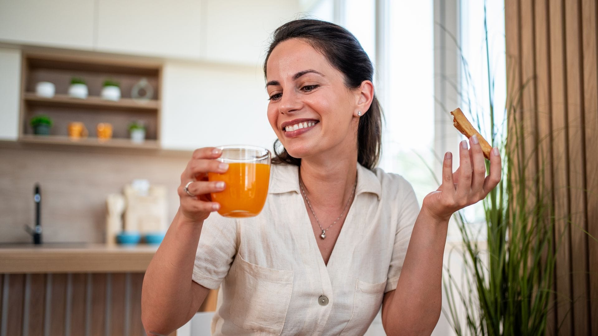 Una mujer tomando un zumo de naranja y una tostada de mermelada