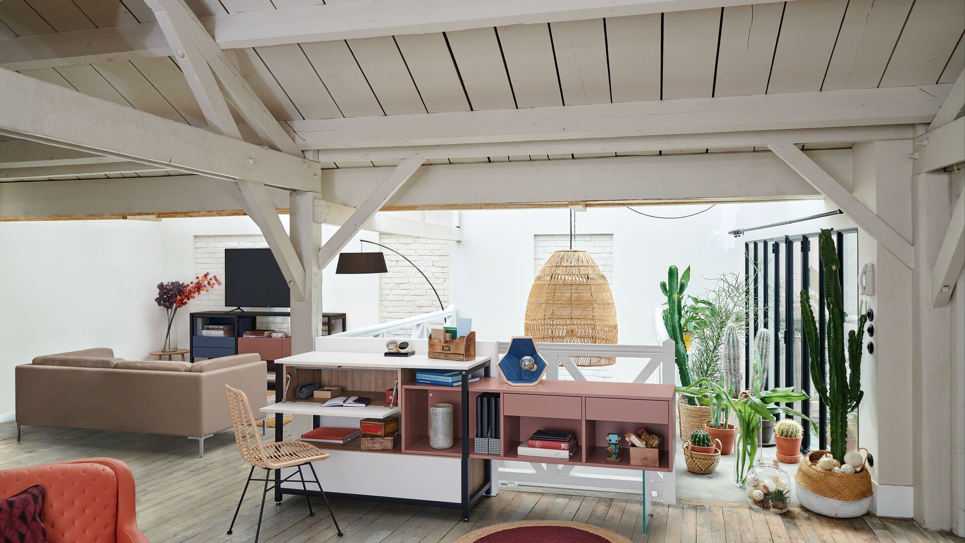 Despacho en buhardilla con mueble multifunción, plantas y cactus, lámpara de fibras vegetales, techo de madera blanco