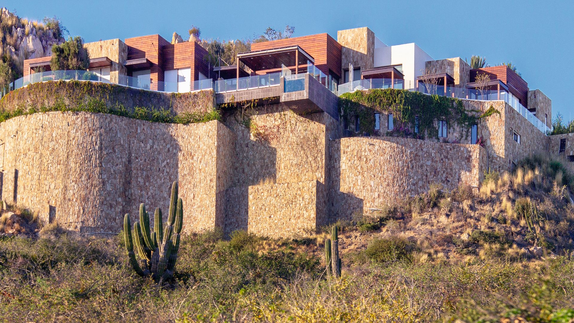 La fachada de la casa, que se encuentra en la montaña, sostenida por un gran muro. Cuenta con varias terrazas y unas vistas privilegiadas