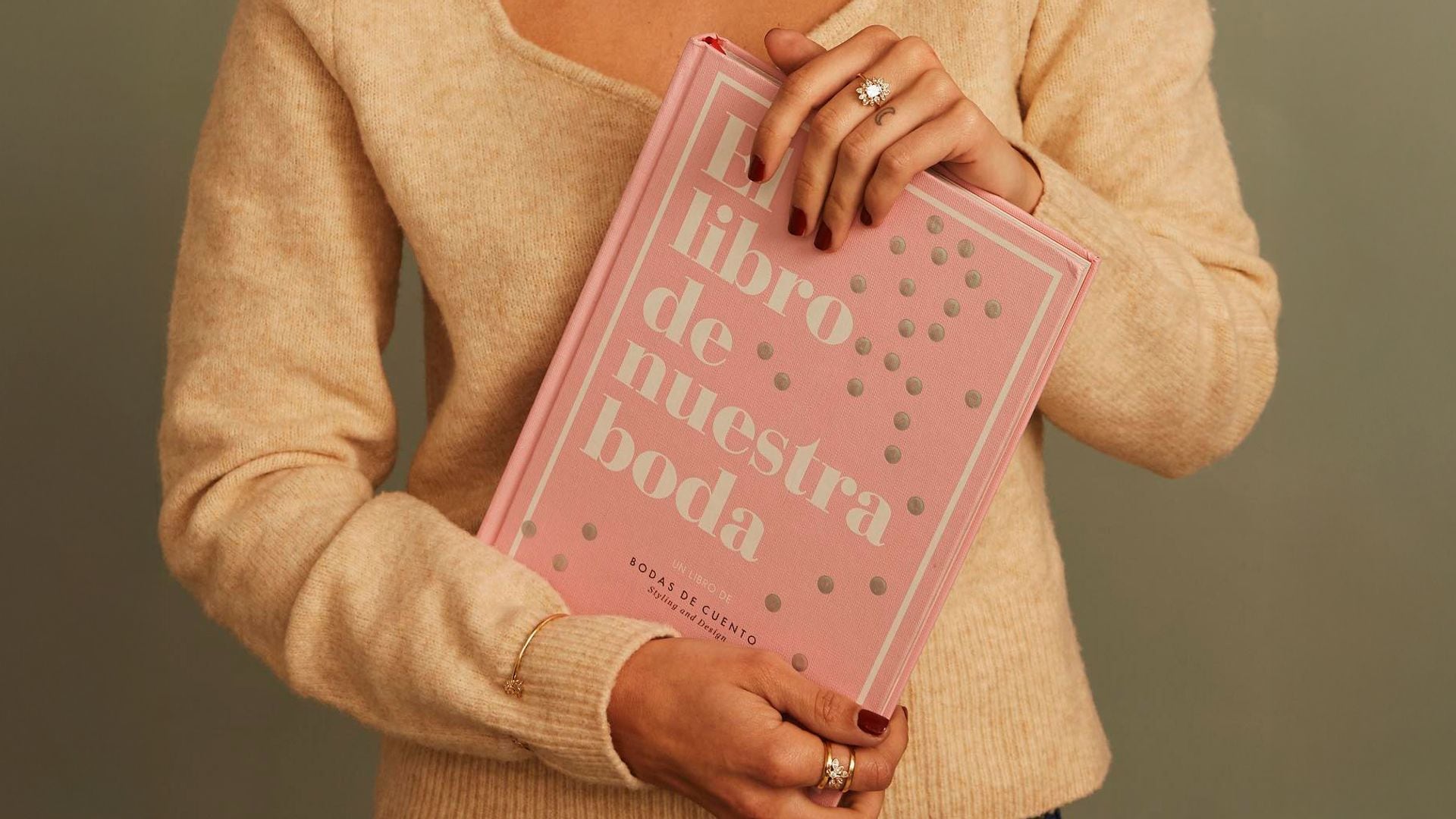 Mujer con El libro de nuestra boda, jersey de punto y joyas de Apodemia