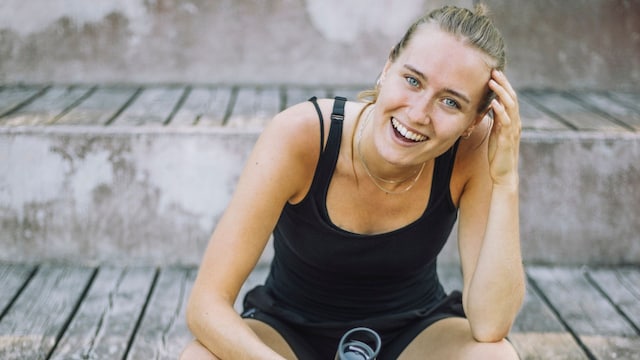 Mujer en ropa deportiva y sonriendo a cámara 