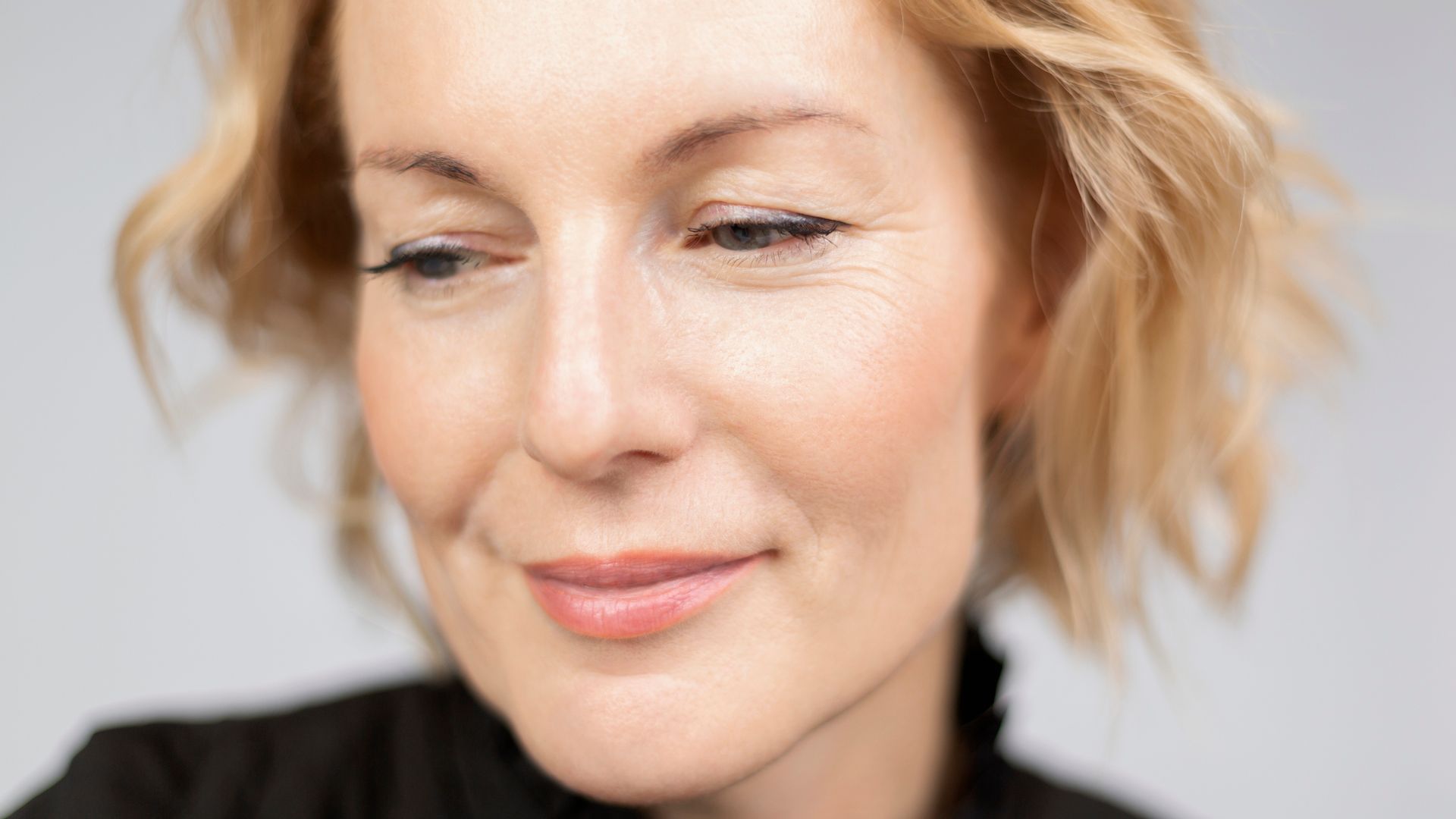 Rostro de mujer rubia con pelo corto y piel alisada, jugosa y radiante