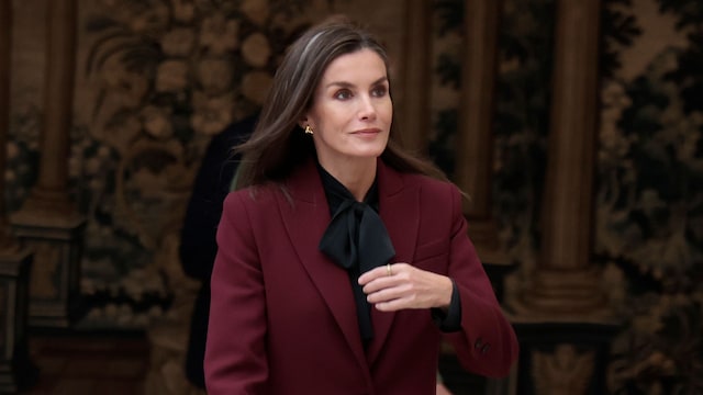 Plano entero de la reina Letizia con un traje burdeos y blusa de lazo