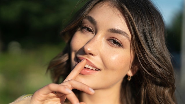 Rostro de mujer morena joven con dedo índice sobre los labios