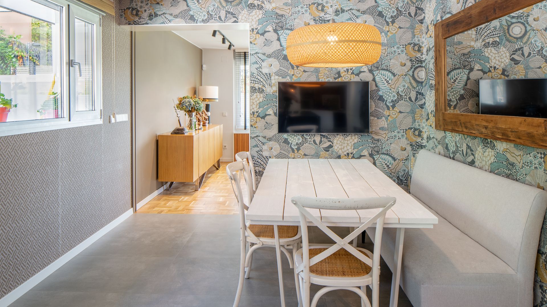 Office con banco tapizado, papel pintado, mesa de madera blanca, espejo y lámpara de techo de fibras vegetales