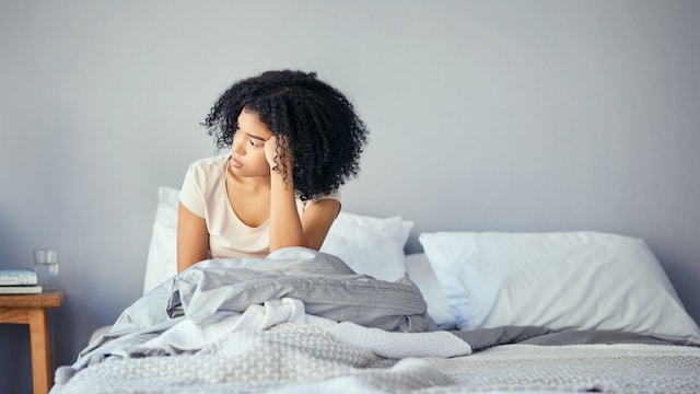mujer pensativa sentada en la cama