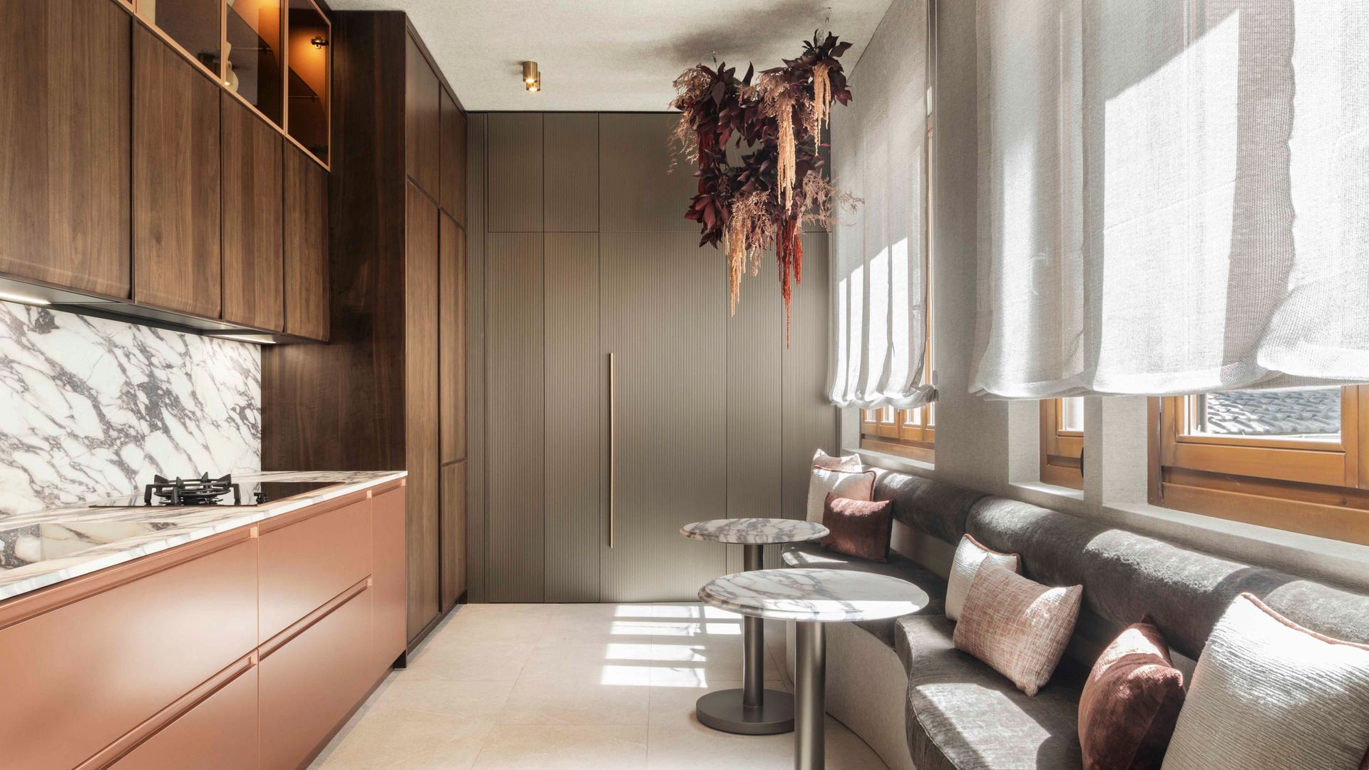 Cocina con muebles tierra, antepecho de mármol, banco bajo la ventana, estores